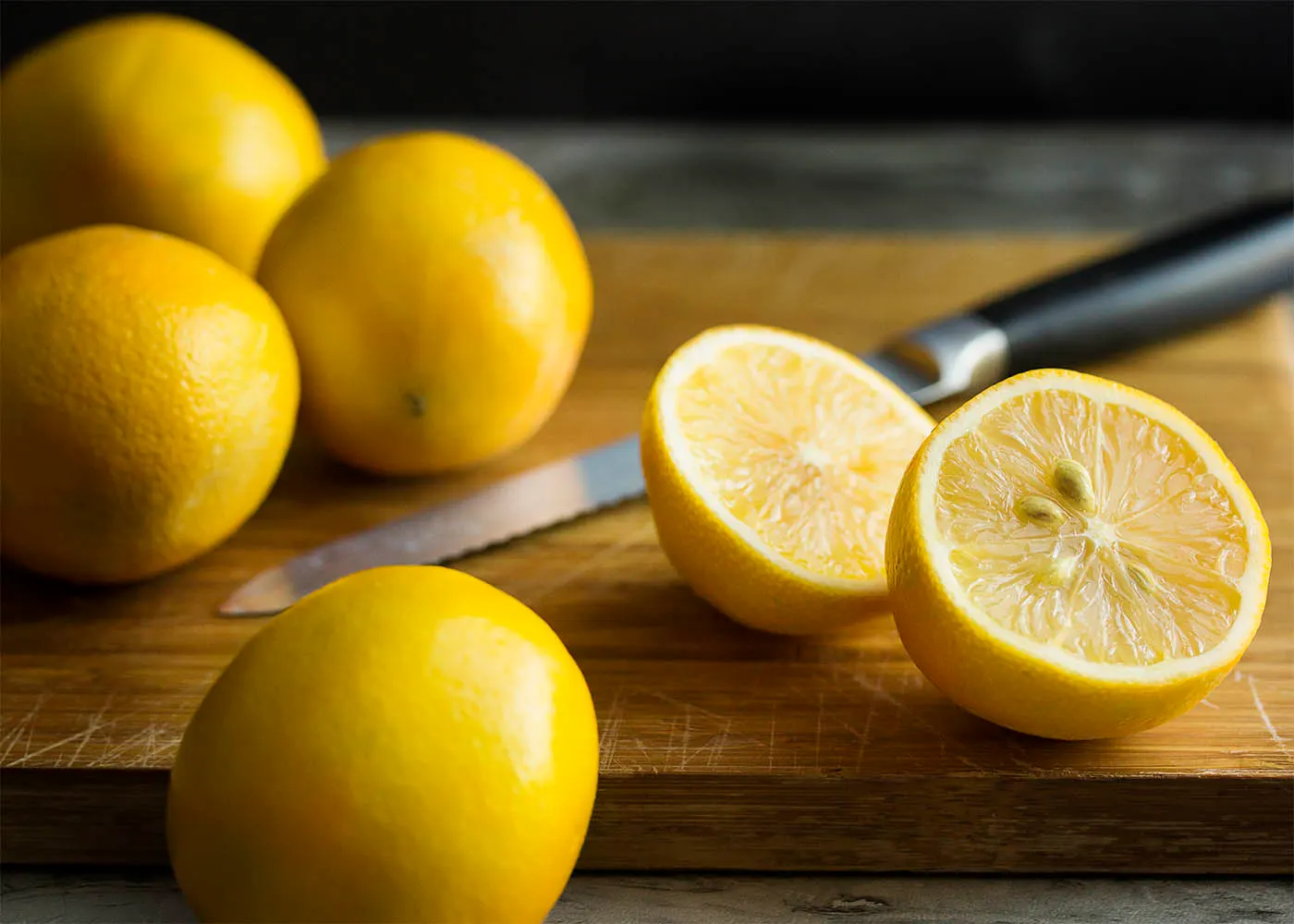 Meyer lemons on a wooden cutting board, one cut open